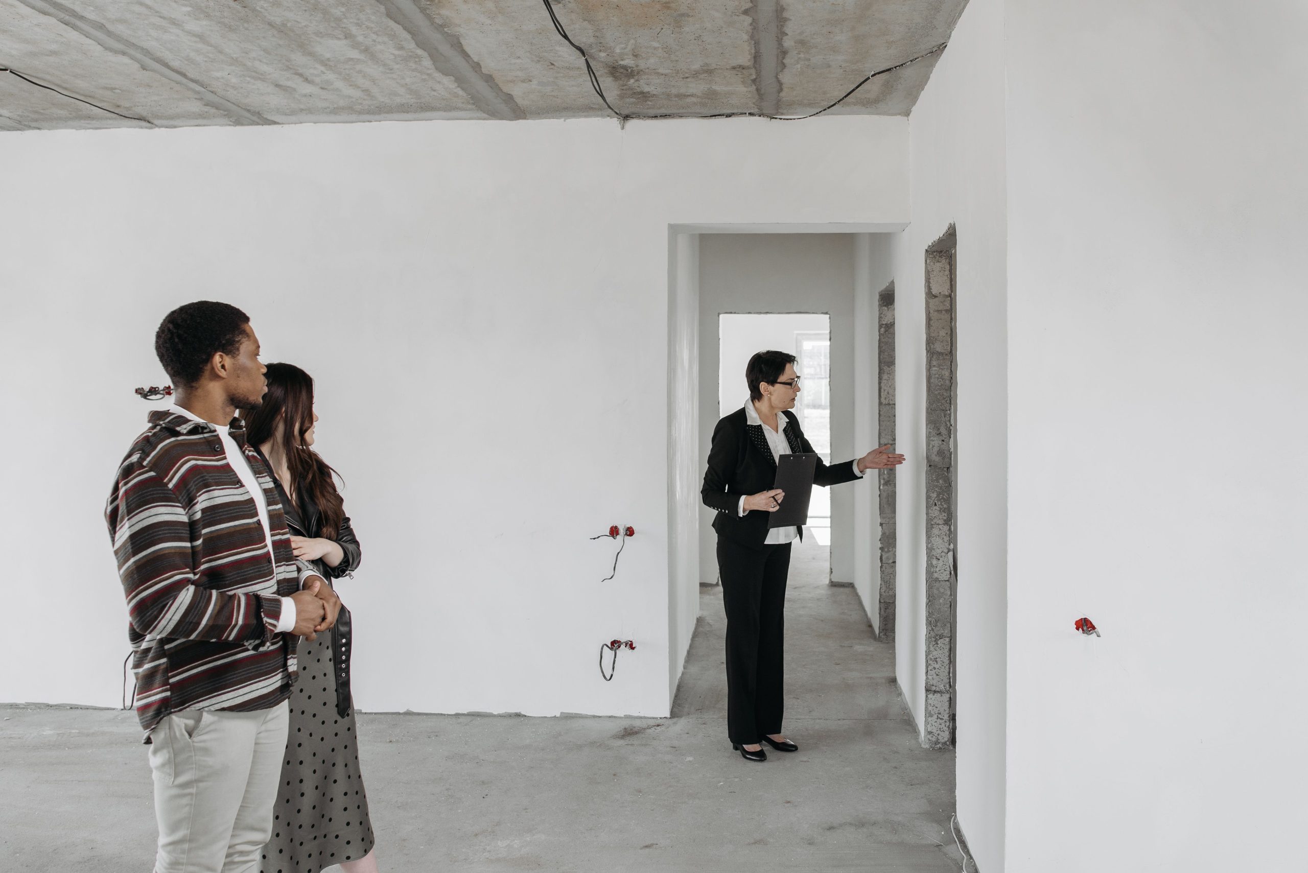 A couple explores an unfinished apartment with a real estate agent, considering property purchase options.