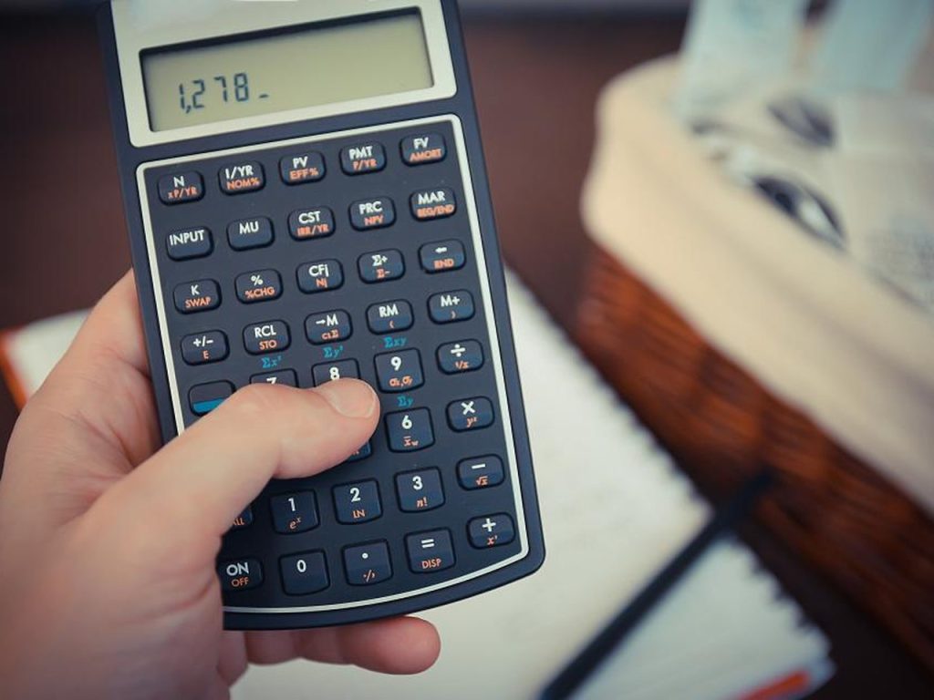Hands using a calculator on a desk with papers